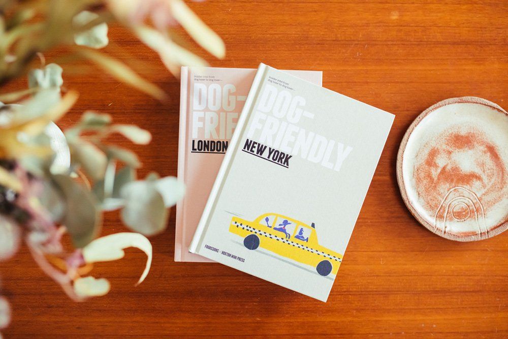 Four&Sons Dog-Friendly New York and Dog-Friendly London city guides displayed on a wooden tabletop with plants.