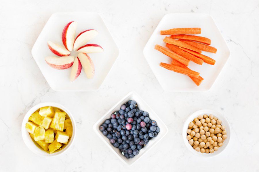 Fresh apples, carrots, and blueberries in bowls, perfect healthy ingredients for DIY dog treats and pet wellbeing.