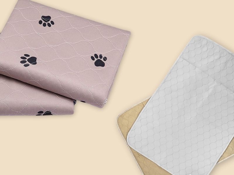 Washable pee pads for dogs in pink with paw prints and white quilted reusable training mats.