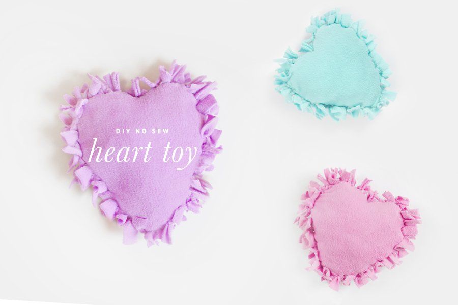 Three heart-shaped fleece dog toys in purple, teal and pink, with fringed edges.