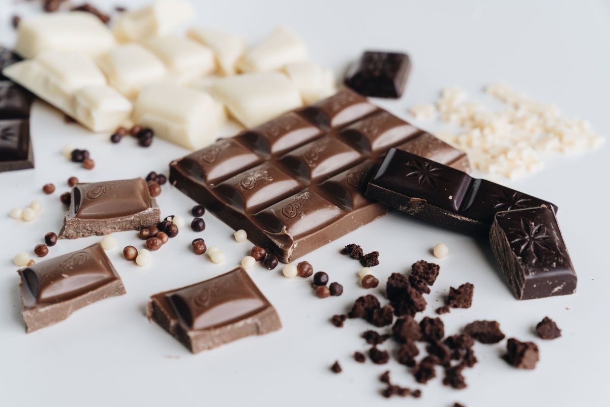 An assortment of dark, milk, and white chocolate pieces on a white background.