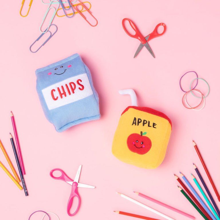 Cute plush dog toys shaped like a chip bag and apple juice box on a pink background, featured in editor’s picks.