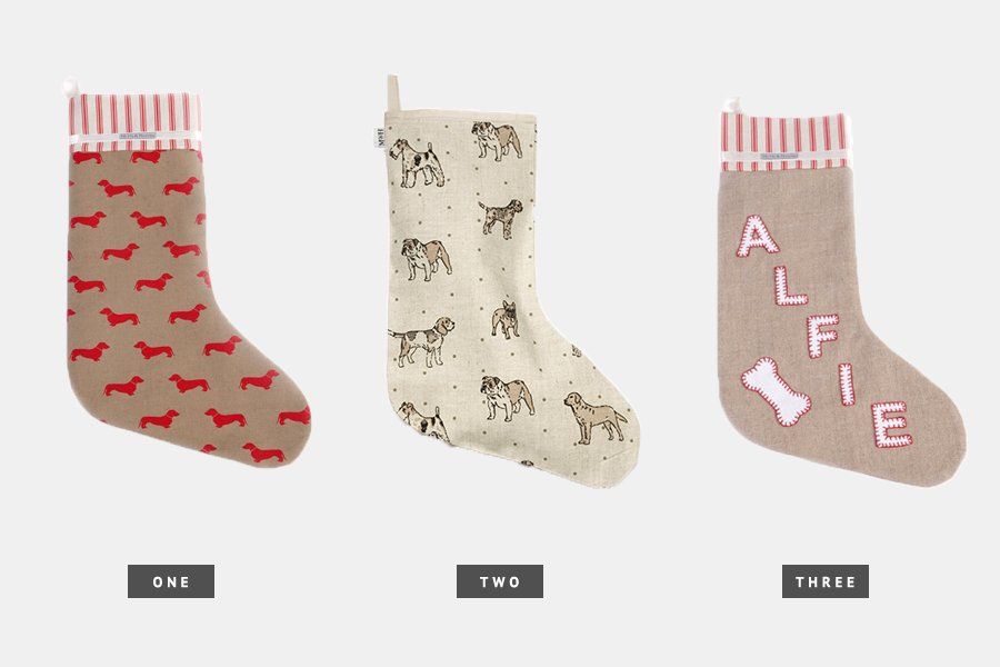 Cream linen Christmas stocking featuring dog breed illustrations, a stylish holiday trend for pet parents.