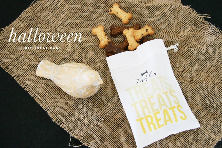 Printable DIY Halloween dog treat bag with yellow text, filled with bone-shaped biscuits on a rustic burlap background.