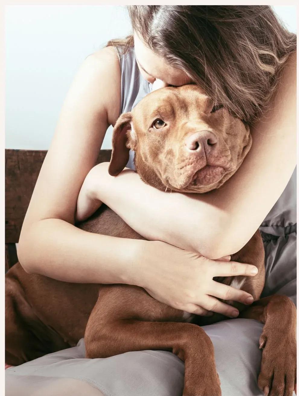 Woman hugging her brown dog, illustrating the emotional health and wellbeing benefits of pet companionship.