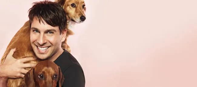 Celebrity Peter Alexander smiling while holding his beloved dachshund Penny and a fluffy dog.