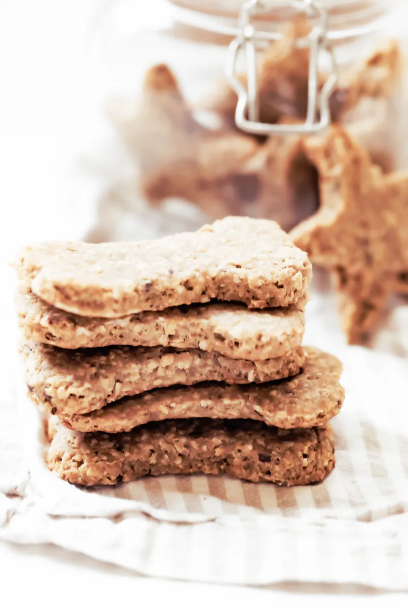 pile of homemade peanut butter and banana dog treats with jar in background