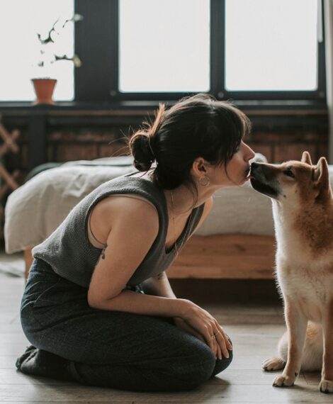 Woman kneeling on the floor kissing her Shiba Inu's nose, illustrating dog love for inspirational dog captions.